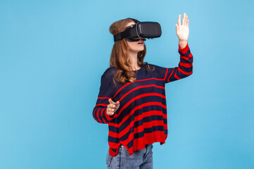 Portrait of woman wearing striped casual style sweater and vr headset and touching air with hands,...