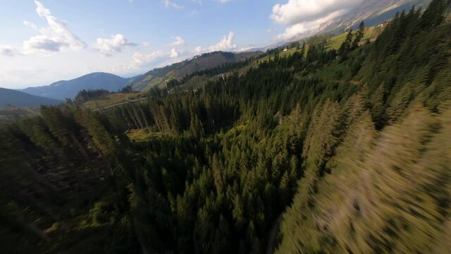 FPV drone flying over trees during sunset at lake Lago di Carezza, Italy. Beautiful landscape with mountains in the background. 