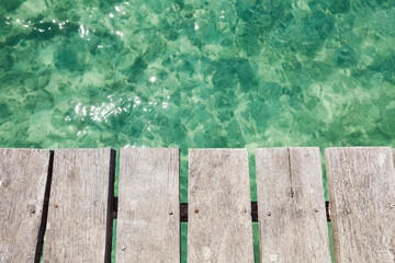 Wooden pier over shallow clear turquoise blue water 