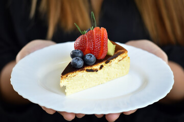 Middle view, Basque Burnt Cheesecake on white plate with woman hand.