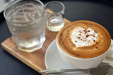 Close-up view, Warm coffee cup with cold water glass on wooden plate.