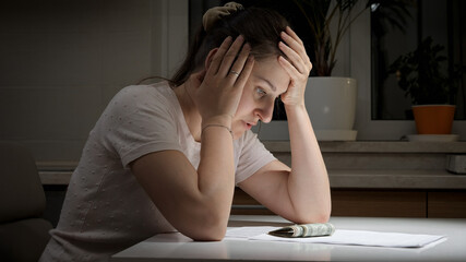 Portrait of stressed woman having few money sitting alone at night