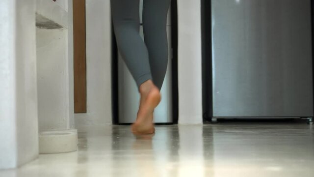 Legs of a young European girl goes to a white kitchen