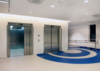 Elevators in the atrium of a new modern hospital, blue patterns on the floor