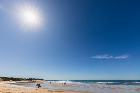 Sun shining against clear blue sky over sandy coastal beach