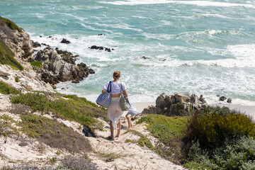 Teenage girl and younger brother exploring a rocky coastline with waves crashing on shore. 