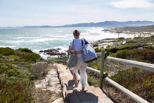Teenage girl and younger brother exploring a rocky coastline with waves crashing on shore. 