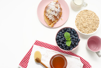Raw oatmeal in white ceramic plate, blueberry, honey on white table, breakfast. top view