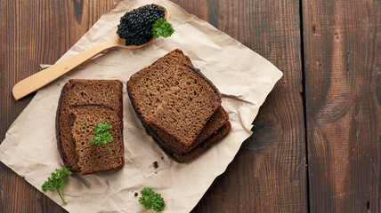 fresh grainy black paddlefish caviar in brown wooden spoon on a brown table
