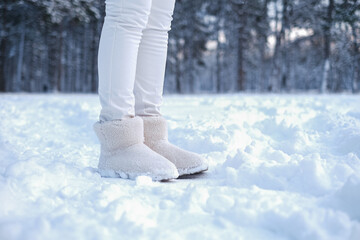 legs of a woman in fur boots on the snow in the forest. girl in warm shoes walks through the snowy forest. warm fur winter shoes