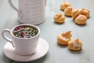 Appetizing profiteroles with whipped cream and a cup of herbal tea