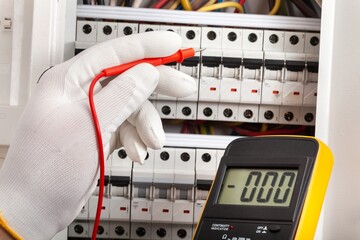 Electrician at work on an electrical panel protected in safety goggles and gloves; Coronavirus....
