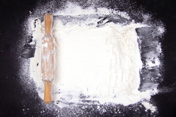 Abstract baking background with copy space on a black surface for text. Spot on black, top view on the board. The concept of baking, the preparation of dough or dough.