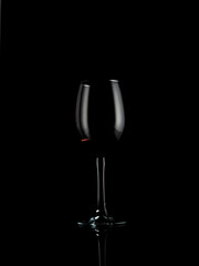 
wine and champagne glass on black background with pouring red wine