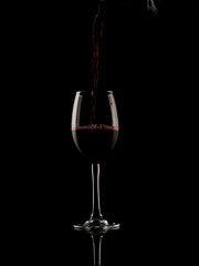 
wine and champagne glass on black background with pouring red wine
