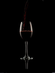 
wine and champagne glass on black background with pouring red wine