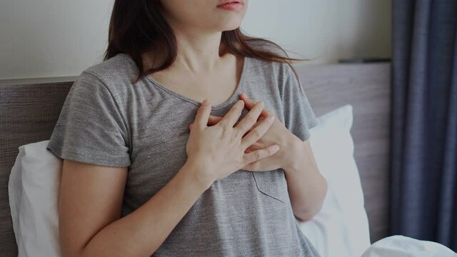 Young Asian woman suffering from heart attack in bedroom