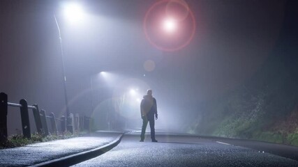 A science fiction edit. Of a man standing in the road. With a glowing, alien UFO floating in the sky at night.