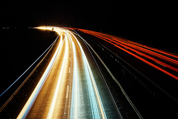 Fototapeta na wymiar Moving cars at night on highway, long exposure. Motion blur effect of light trails. Fast speet traffic