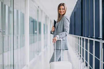 Business woman with travel luggage in airport, holding laptop