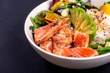 Bowl healthy salad with salmon. Close up on black background