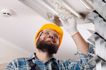 An electrician is installing lamp spotlights on the ceiling.