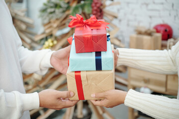 Hands of husband and wife exchanging Christmas presents in the morning