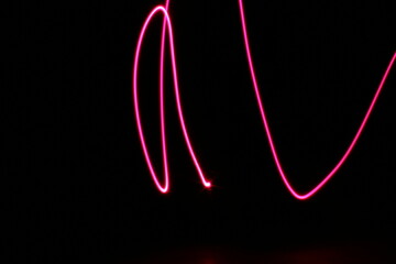 Lìneas de color con luz de neòn en forma de signos en movimiento de càmara y bokeh, forma una ilustraciòn abstracta en el espacio con fondo negro.