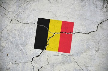 An old image of the flag of Belgium on a wall with a crack.