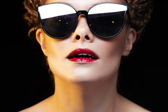 Beautiful joyful young woman in sunglasses. Bright lips with red lipstick, portrait on black