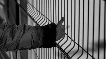 Black and white closeup imag eof little boy holding metal net fence
