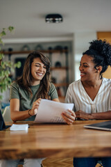 Two diverse friends, having fun at work, while laughing.