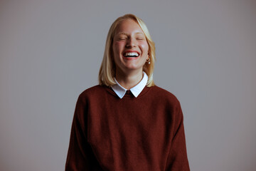 Portrait of happy caucasian woman, laughing out loud in a neutral background.