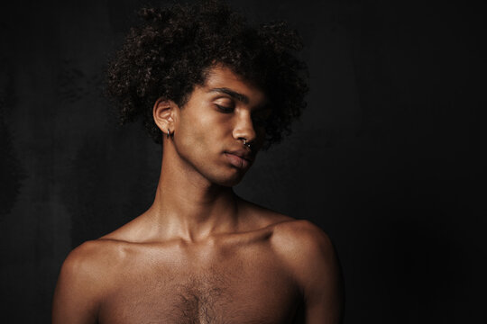 Shirtless black man with piercing posing and looking downward