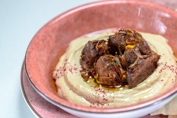 hummus with meat on a pink plate
