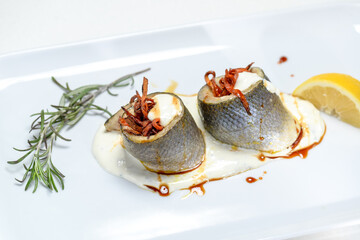beautifully served herring on a white plate close-up with a sprig of rosemary
