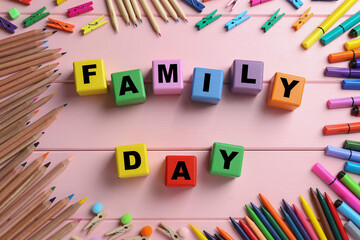 International Family day. Flat lay composition with cubes, pencils, crayons and clothespins on pink wooden background
