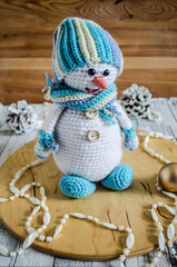Knitted snowman with cones and a Christmas tree on a light background.