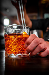 man hand bartender making negroni cocktail in bar
