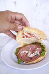 Simple beef burger  with ham and lettuce are served on a white plate. Bakery, Fast food concept. Street food concept.