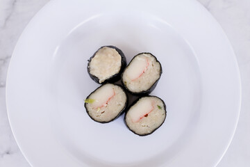 Chicken nori rolls or sushi rolls with shrimp, cheese, caviar, chicken, soy sauce, nori, wasabi on a white plate