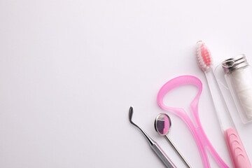 New tongue cleaner and teeth care products on white background, top view