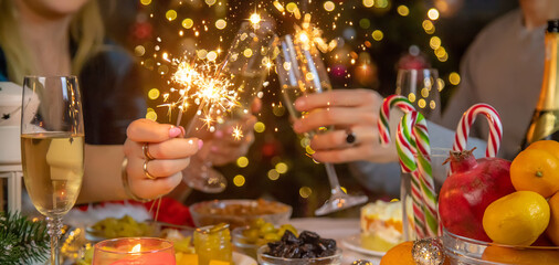 Champagne in hand against the background of the Christmas tree. People. Selective focus.