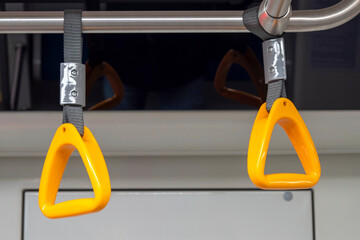 Close-up of an empty yellow handrail or handles for passenger in metro. Concept about social...