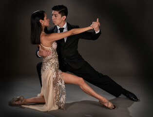Latin woman and asian man dancing tango ballroom. studio shot