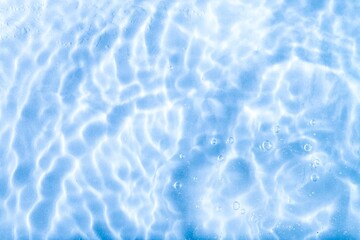 Blurred blue clear calm water surface texture with splashes and bubbles. abstract nature background. Water waves.