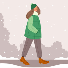 Naklejka na ściany i meble Girl in a green coat walking in a winter park. First snow. Christmas mood. Stylish hat with a pompom.