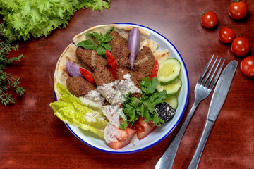 falafel on a plate with vegetables and herbs in a white sauce on a plate
