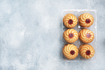 Kurabye shortbread cookies with berry jam in a plastic package. Delicious dessert, gray concrete background with copy space.