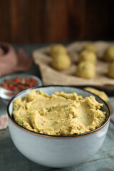 Bowl of chickpea puree on blue wooden table, space for text. Falafel recipe